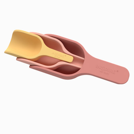 Stacked measuring cups in soft pink and yellow, featuring curved handles and a smooth finish. They convey a playful, modern kitchen aesthetic.