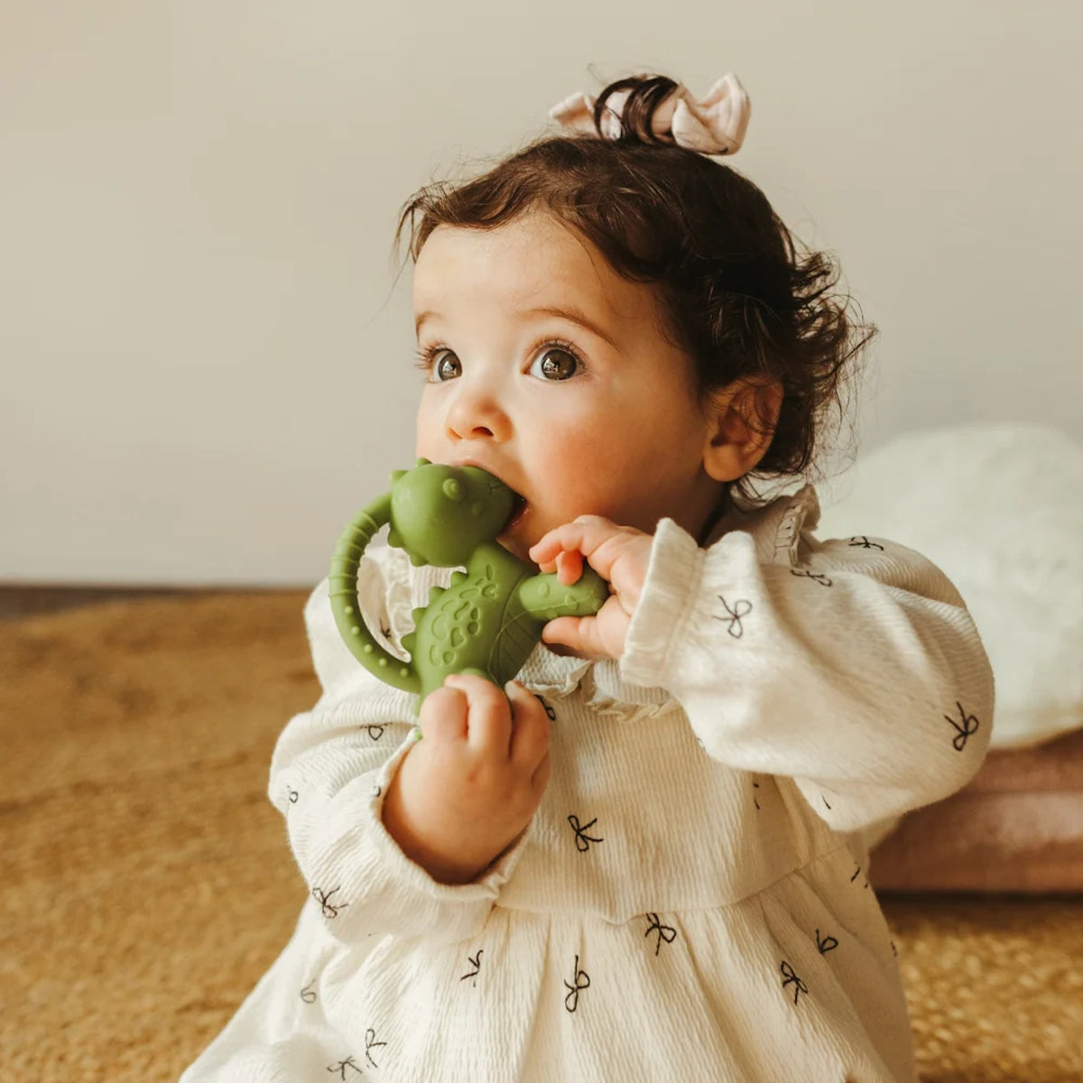 Baby chewing on a green Jellystone Designs dinosaur teether.