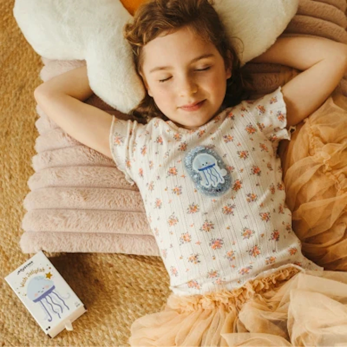 Child lying down resting with a blue Wish Jellyfish sensory pouch resting on her chest.