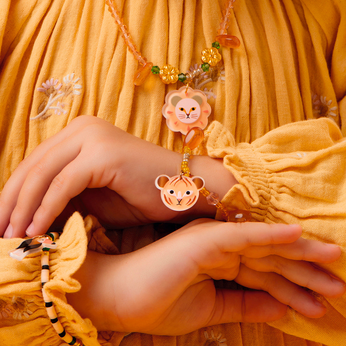 Child wearing a Deborah jungle collection necklace and bracelet with lion and tiger charms.
