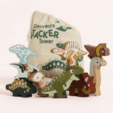 Wooden dinosaur toy figures stacked in groups in front of a printed drawstring bag.