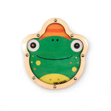 Cute frog illustration on a round, wooden toy with metal balls inside. The frog is green with big eyes, yellow spots, and a friendly smile.