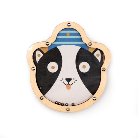 Wooden toy with a cartoon dog's face, featuring large eyes and a smiling mouth. It's outlined with metallic studs and includes small metal balls.
