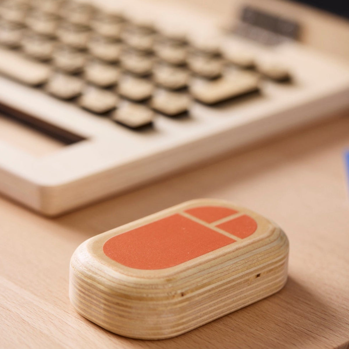 Wooden toy mouse next to a toy laptop keyboard on a wooden desk.