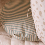 Round green and beige striped floor cushion with a fabric handle, resting on a padded mat.