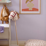 Spotted hobby horse toy and matching floor cushion in a pastel-toned child's room.