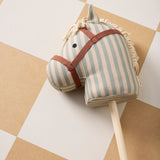 Striped fabric hobby horse head on a wooden stick lying on a tiled floor.