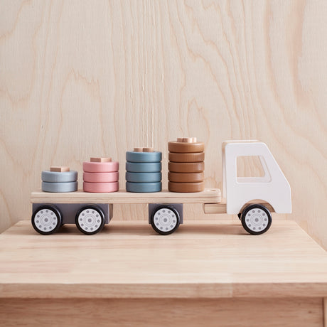 Side view of a wooden toy truck with colorful shape-sorting rings stacked on its flatbed trailer.