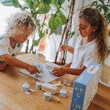 Two young children sitting at a wooden table, playing with an electronic building blocks toy kit.