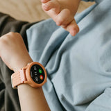 A child wearing a coral-colored smartwatch with a stopwatch timer running on the screen.
