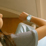 A child looking at a light blue smartwatch on their wrist, showing a dog icon and the time 16:45.