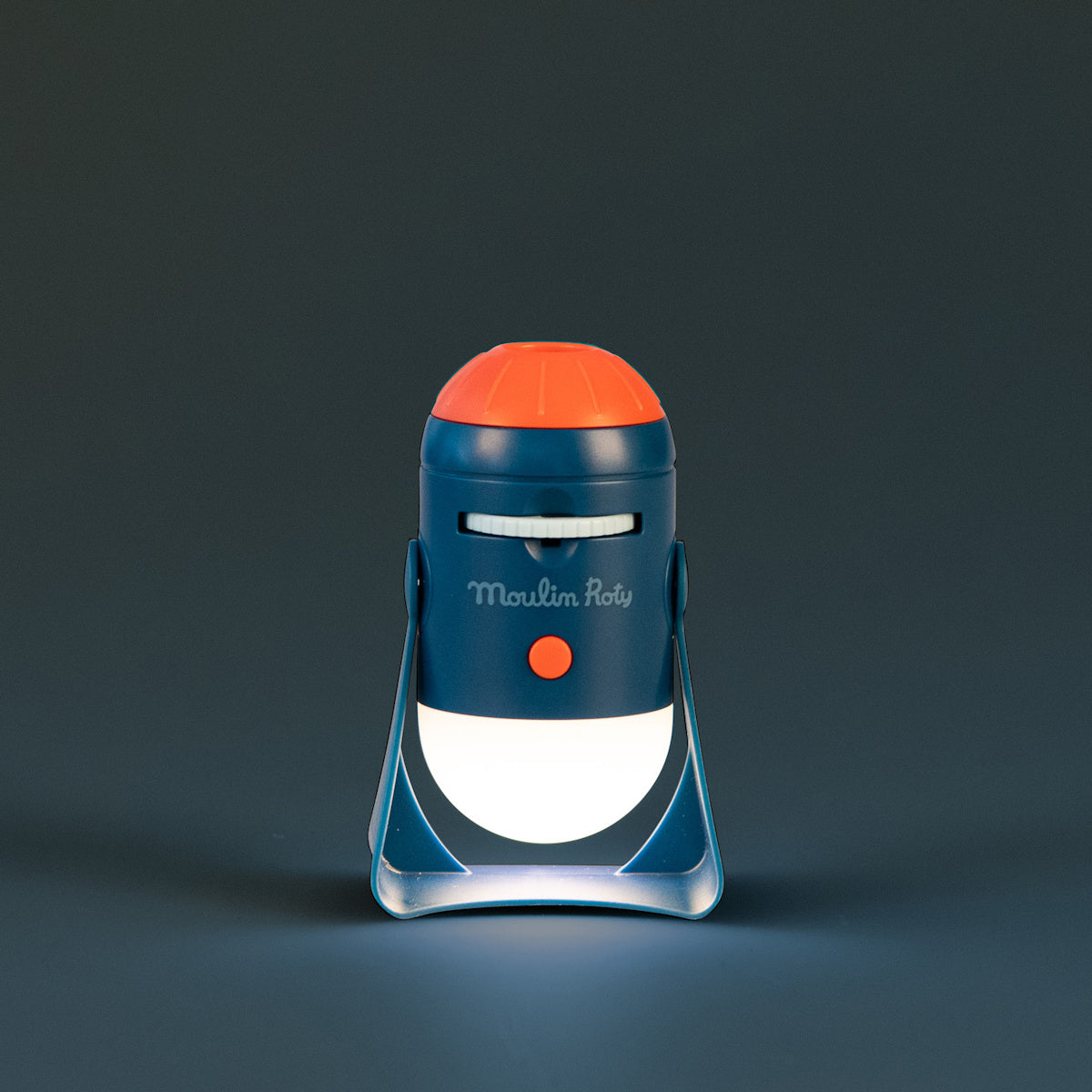 Moulin Roty Les Explorateurs space projector toy glowing in the dark in navy blue and orange rocket design for kids.