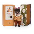 Moulin Roty Leon the cat plush toy in a tweed coat standing between its orange and floral illustrated boxes.