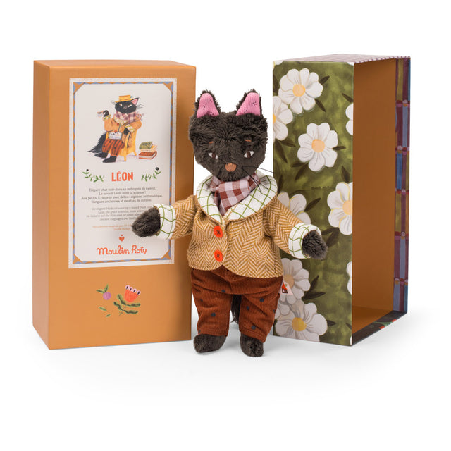 Moulin Roty Leon the cat plush toy in a tweed coat standing between its orange and floral illustrated boxes.