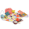 Les Minouchkas fireside accessories with toy lantern, teapot, banjo, books, and colorful quilted play mat.