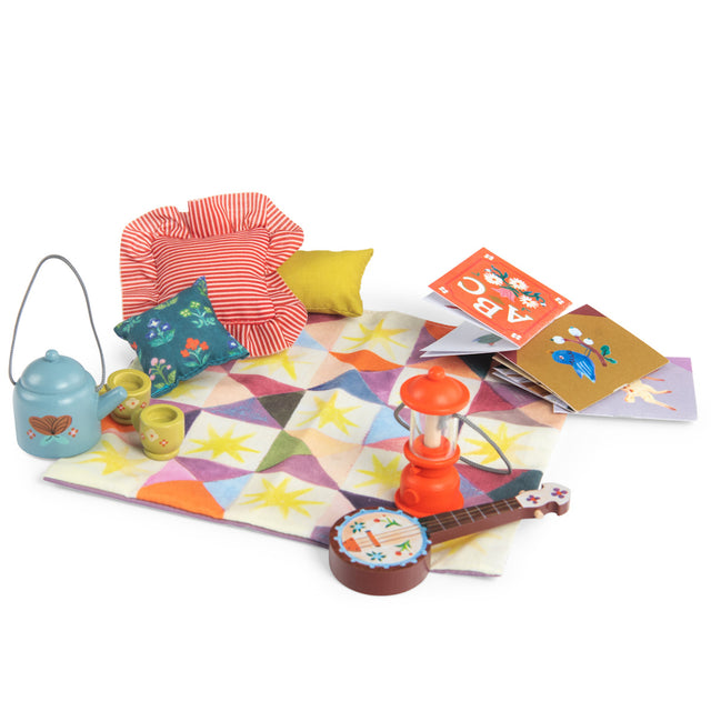 Les Minouchkas fireside accessories with toy lantern, teapot, banjo, books, and colorful quilted play mat.