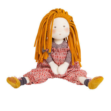 A cloth doll with orange yarn hair, wearing a red patterned dress, gray top, and yellow shoes. The doll sits with legs outstretched, exuding a cute and playful vibe.