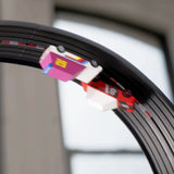 Action shot of Candylab toy cars racing upside down on a black Roadworks Loop track add-on kit.