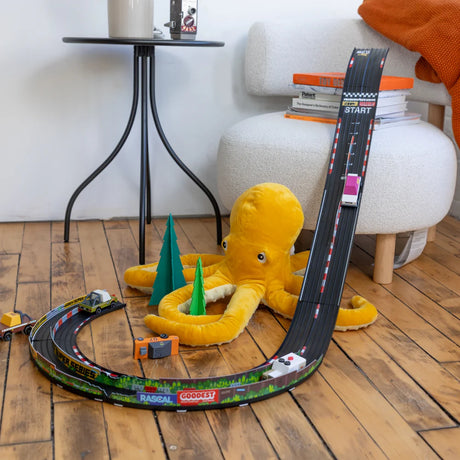 Candylab Roadworks Speed playset with toy cars and yellow octopus plush on a wooden floor in a modern living room.