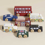 Set of seven wooden London toy vehicles neatly displayed on a beige background.