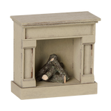 An off-white miniature vintage fireplace with faux logs inside, set against a solid white background.