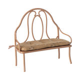 Vintage-style miniature wrought iron bench with a light brown, floral-patterned cushion. The elegant curves of the metal frame add a classic charm.