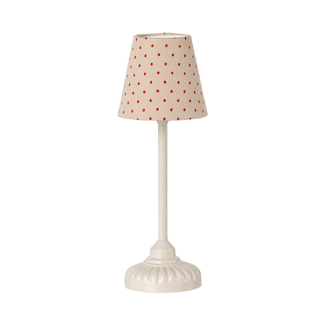 A miniature beige table lamp with a red polka dot shade and an ornate white ceramic base, creating a whimsical yet classic feel against a plain background.