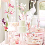 An elegant pink princess-themed party table set with pastel cakes, flowers, and matching tableware.