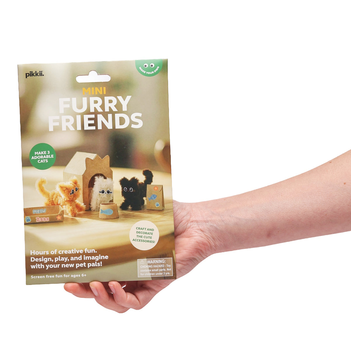 Hand holding Mini Furry Friends craft kit packaging featuring three miniature toy cats.