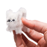 Hand holding a tiny white fluffy pipe cleaner cat figure with paper eye stickers.