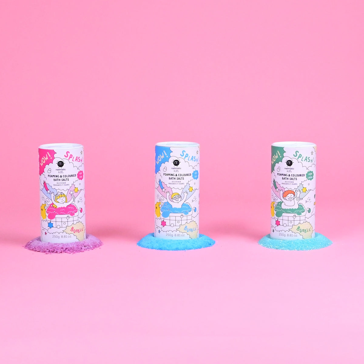 Three colorful bath salt containers on a pink background, each surrounded by matching colored salts, purple, blue, and green. Playful packaging with cartoon graphics conveys a fun, vibrant tone.