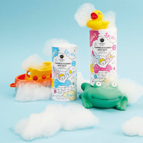 Toy bath scene with foaming bath salt containers, a yellow rubber duck, and a green frog toy. Background features playful bubbles and an orange boat.