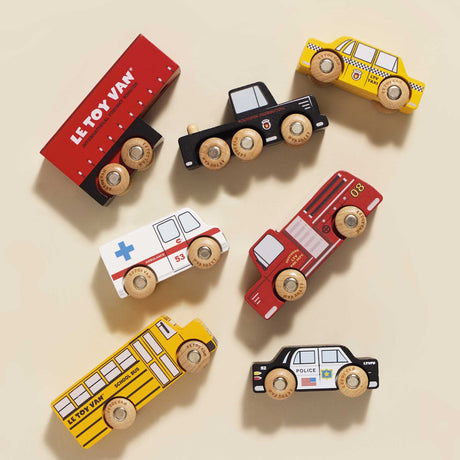 Top-down view of six wooden toy vehicles arranged neatly on a beige surface.