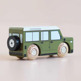 Rear three-quarter view of a green wooden toy car with a spare tire mounted on the back.