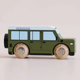Side profile of a green wooden toy car with a white roof and natural wood wheels.