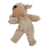 Cute doll in a fluffy beige sheep costume with floppy ears and a serene face. The doll wears a small embroidered rainbow, conveying calmness.