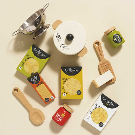 Top-down view of wooden toy pasta play set with pot, colander, utensils, jars, and pasta boxes.