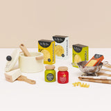 Wooden toy pasta play set with cooking pot, sauce jars, boxes, colander, and towel.