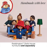 Wooden Paddington Bear standing in front of family dolls gathered around a couch with mini accessories.
