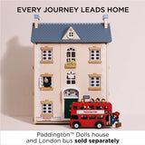 Wooden Paddington Bear boarding a red double-decker toy bus in front of a three-story dollhouse.