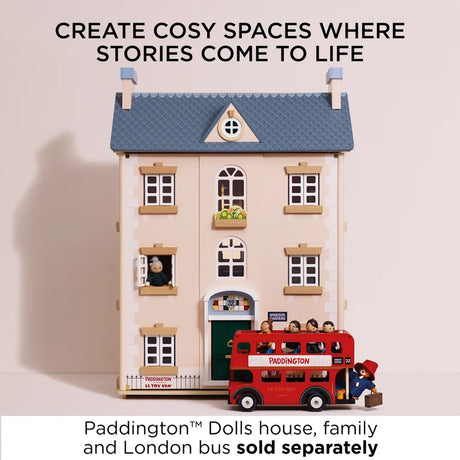 Wooden dollhouse with a London bus and Paddington figure outside.
