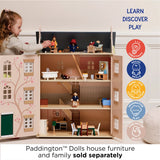 Young girl playing with a wooden dollhouse filled with miniature furniture and figures.