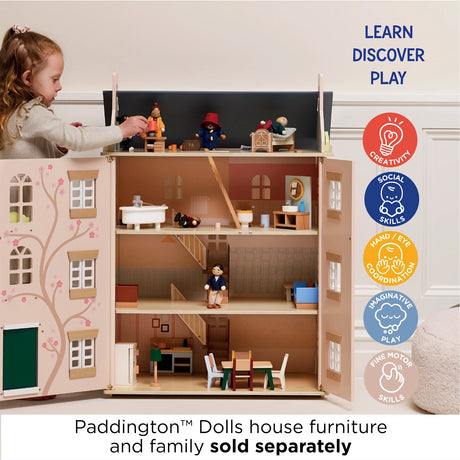 Young girl playing with a wooden dollhouse filled with miniature furniture and figures.