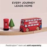 Paddington toy bus on wooden tracks near a red pillar box and tree, with "EVERY JOURNEY LEADS HOME"