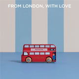 Paddington toy bus on a blue surface against a striped background, with text reading "FROM LONDON, WITH LOVE".