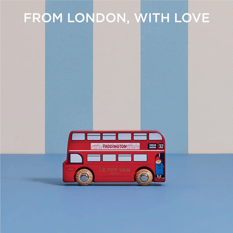 Paddington toy bus on a blue surface against a striped background, with text reading "FROM LONDON, WITH LOVE".