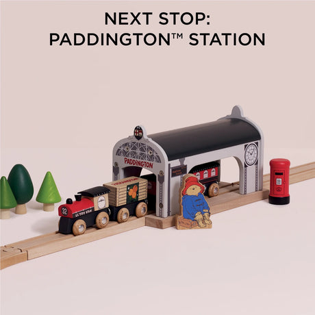 Wooden train pulled up to Paddington station with a Paddington Bear figurine and red post box.