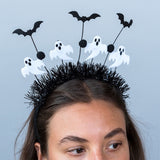 Woman wearing a spooky Halloween headband with black tinsel, white ghosts, and bat boppers.