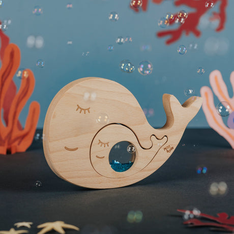 Wooden whale and baby puzzle assembled amidst floating bubbles and underwater decor.