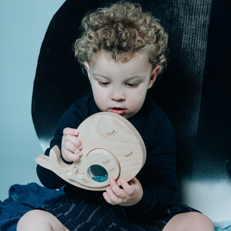 Toddler holding and looking at the whale sensory puzzle.